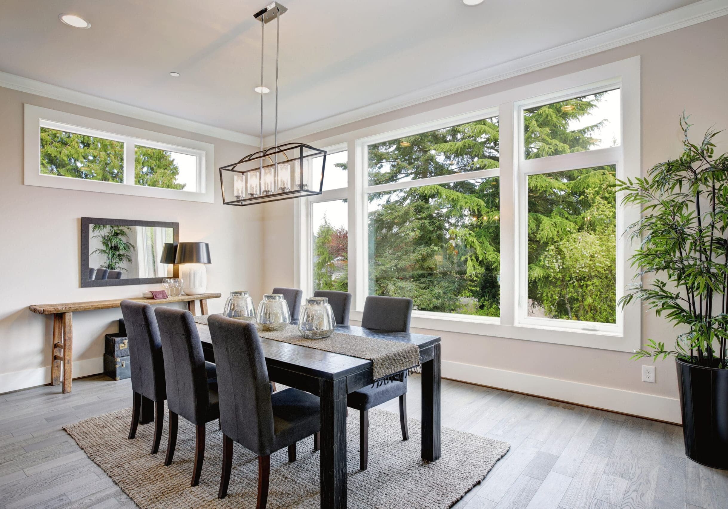 Bright dining room in Monroe, Georgia, with expansive modern windows overlooking green trees and a contemporary table set.