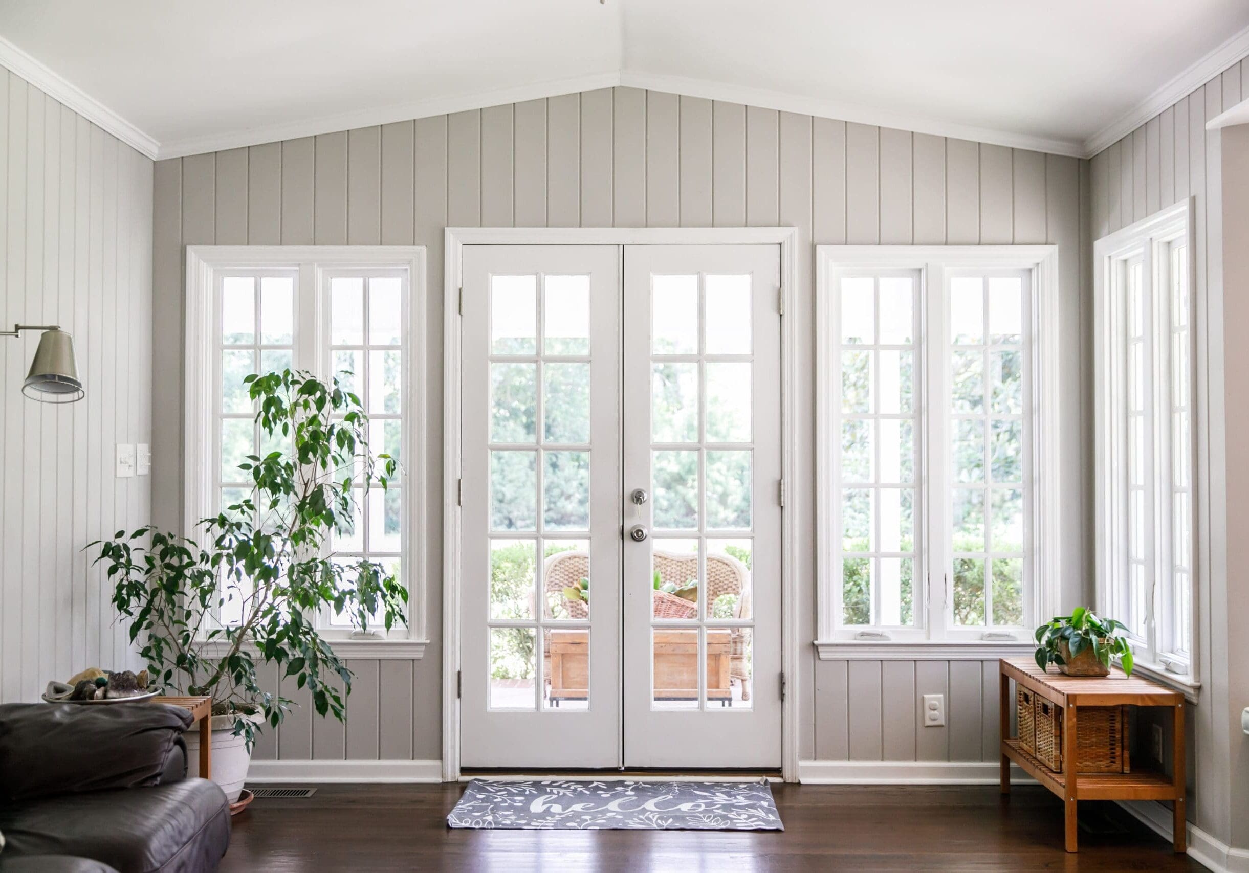 Bright sunroom in Monroe, Georgia, featuring French doors and tall grid windows with white trim, potted plants, and wood floors.
